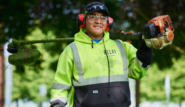 Relay landscaping employee holding a mower