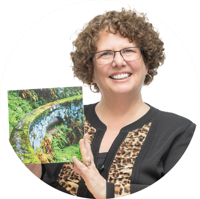 Julie Cody holding a painting of a trail.